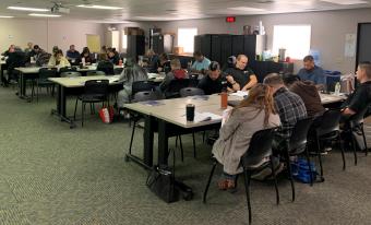 A room of participants looks toward a screen during the workwhop.