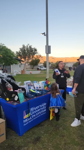 EMD staff show preparedness items to a family standing at the event booth.