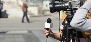 reporter and camera person with no face shown