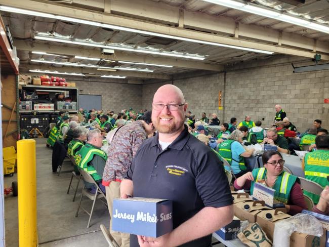 A team member stands in front of CERT Field Day activities.