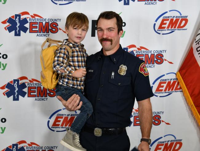 A man standing holding a boy in his arm. 