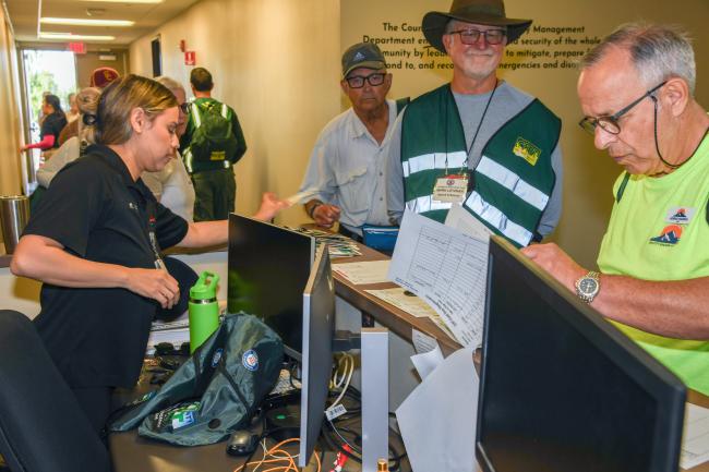 CERT members sign at a desk with an EMD employee assisting.