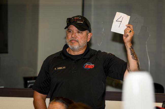 A male EMD employee holds up a sign to assist attendees.