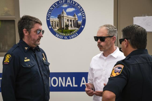 EMD Director, Dan Bates talks with CAL FIRE leadership in front of a trailer.