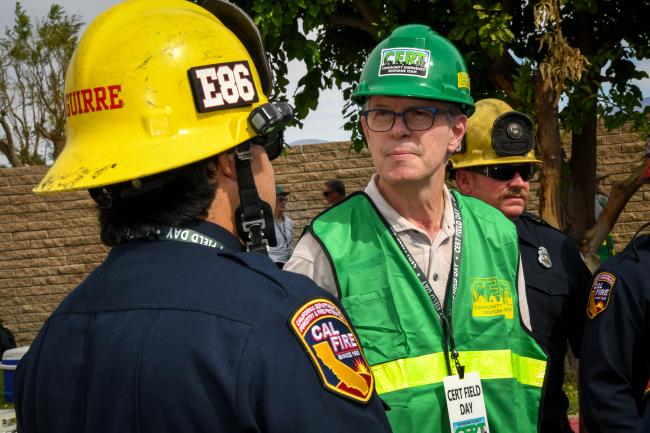 A fire fighter talks with a person in CERT attire.