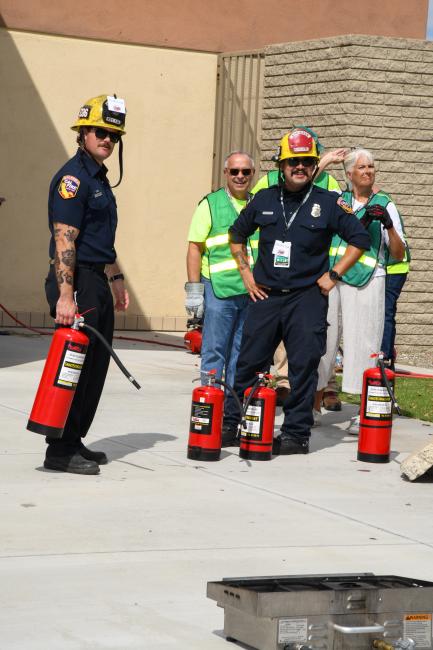 Firefighters stand near fire extinguishers with CERT members standing nearby.