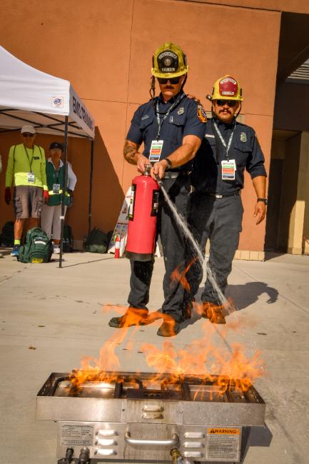 Firefighters demonstrate how to use a fire extinguisher on a fire.