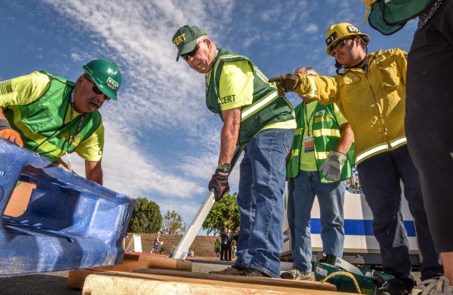 CERT members use a leverage tool to lift a heavy object.