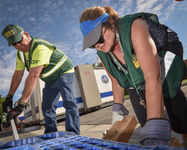 CERT members use a leverage tool to lift a heavy object.