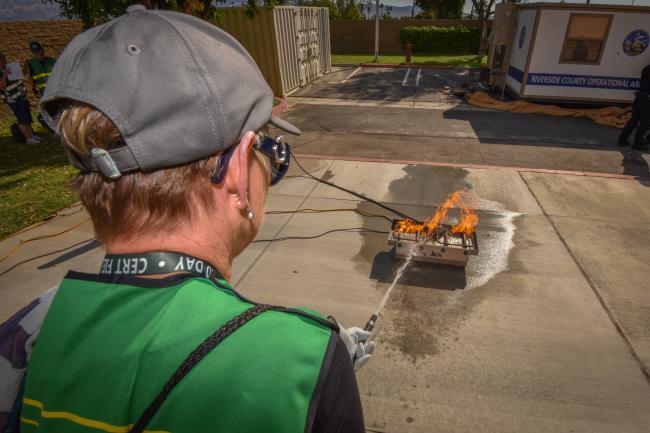 A CERT volunteers uses a fire extinguisher to put out a fire.