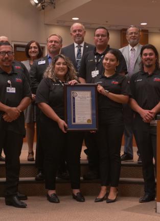 Photo showing Emergency Management Department staff in uniform, along with County Board Supervisors posing for a photo with the frames National Preparedness Month proclamation.