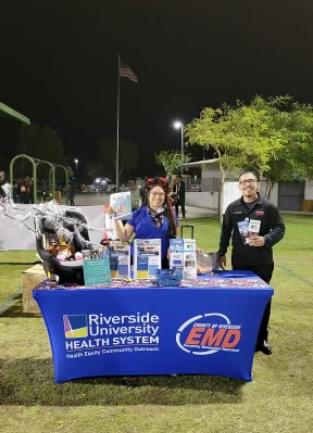 EMD and Public Health employees stand at a table with preparedness items displayed.